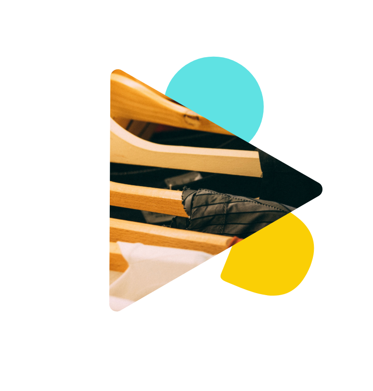 Ein Bildausschnit von hölzernen Kleiderbügeln auf denen T-Shirts hängen.