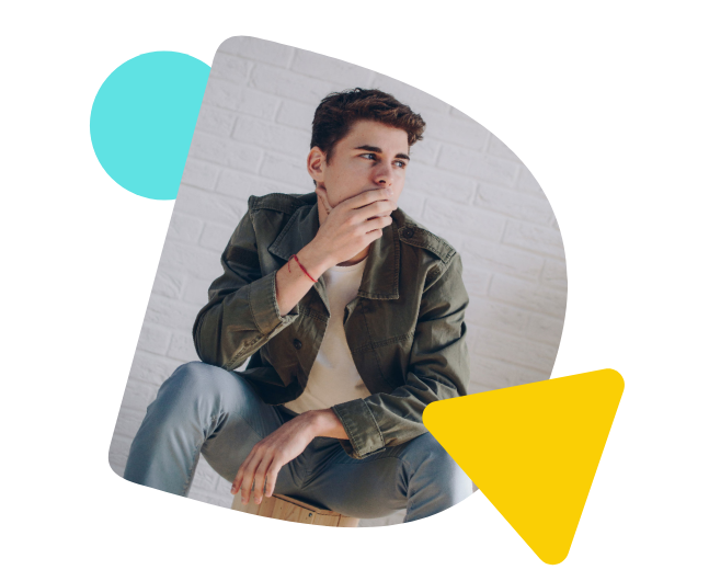 Ein Mann sitzt auf einem Hocker und schaut nachdenklich zur Seite.