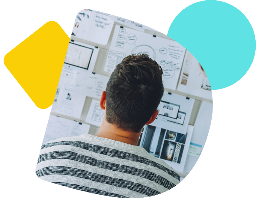 Der Hinterkopf eines Mannes der vor einer Wand aus Notizen steht.