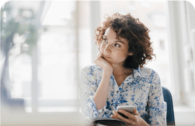 Neurodermitis-Patientin sitzt mit Handy am Tisch