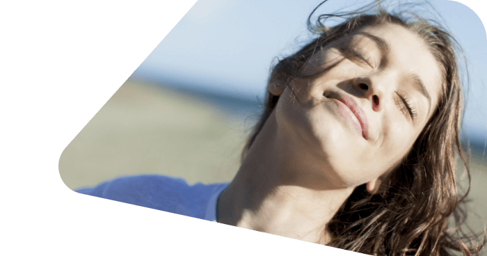 Junge Frau steht zufrieden am Strand