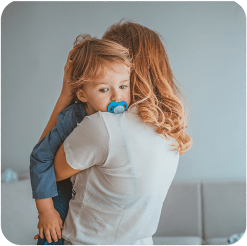 Frau hält ihr von Neurodermitis betroffenes Kind im Arm